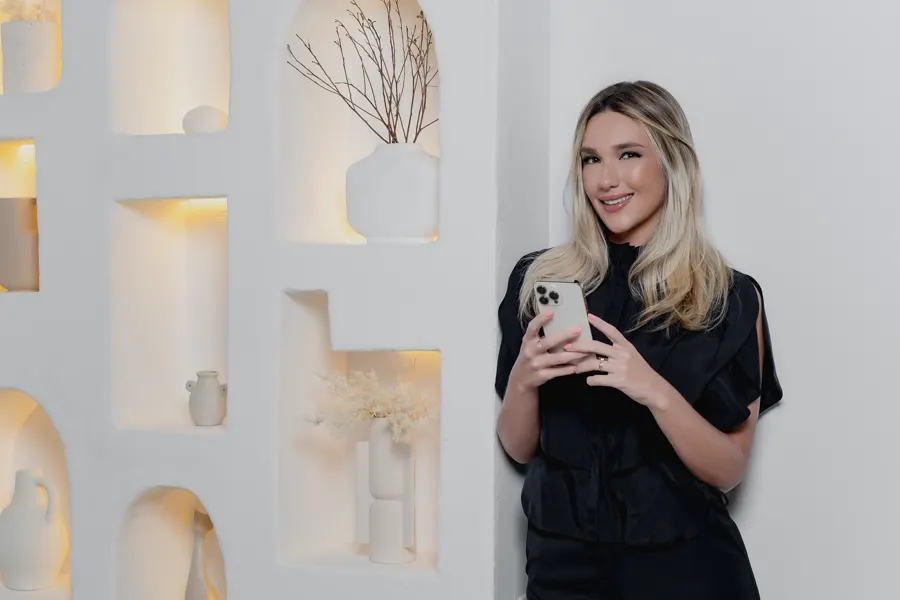 Dra. Vickie White sorrindo, com o celular na mão, diante de nichos iluminados.