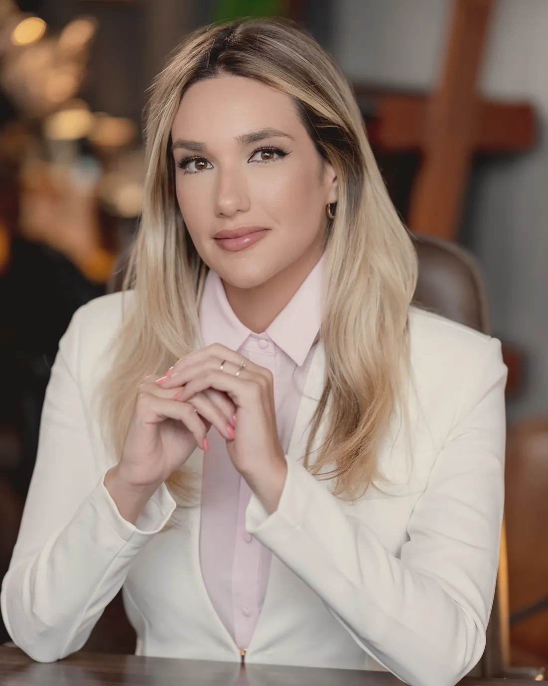 Dra. Vickie White, de blazer branco e camisa rosa, sentada à mesa, com as mãos entrelaçadas.